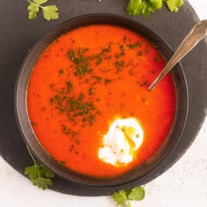 tomato soup with egg in a bowl on a round cutting board.