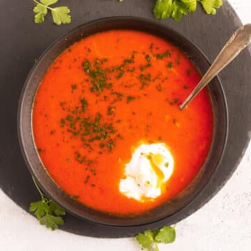 tomato soup with egg in a bowl on a round cutting board.