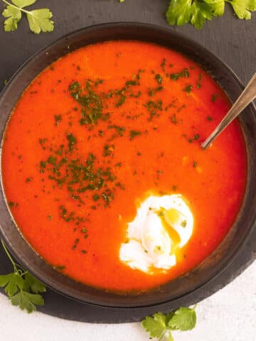 tomato soup with egg in a bowl on a round cutting board.