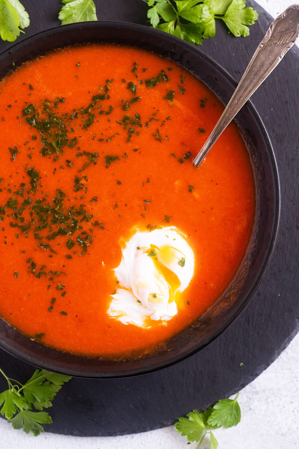 tomato soup with poached egg and cilantro in a bowl with a spoon in it.