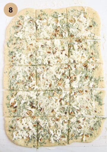 large piece of dough with wild garlic, butter and cheese filling cut into pieces to make pull apart bread.