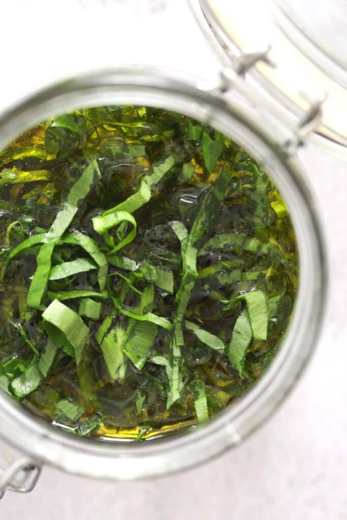 overhead view in a jar with oil and chopped herbs.