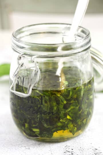 mixing wild garlic with oil to make infused oil in a large jar.