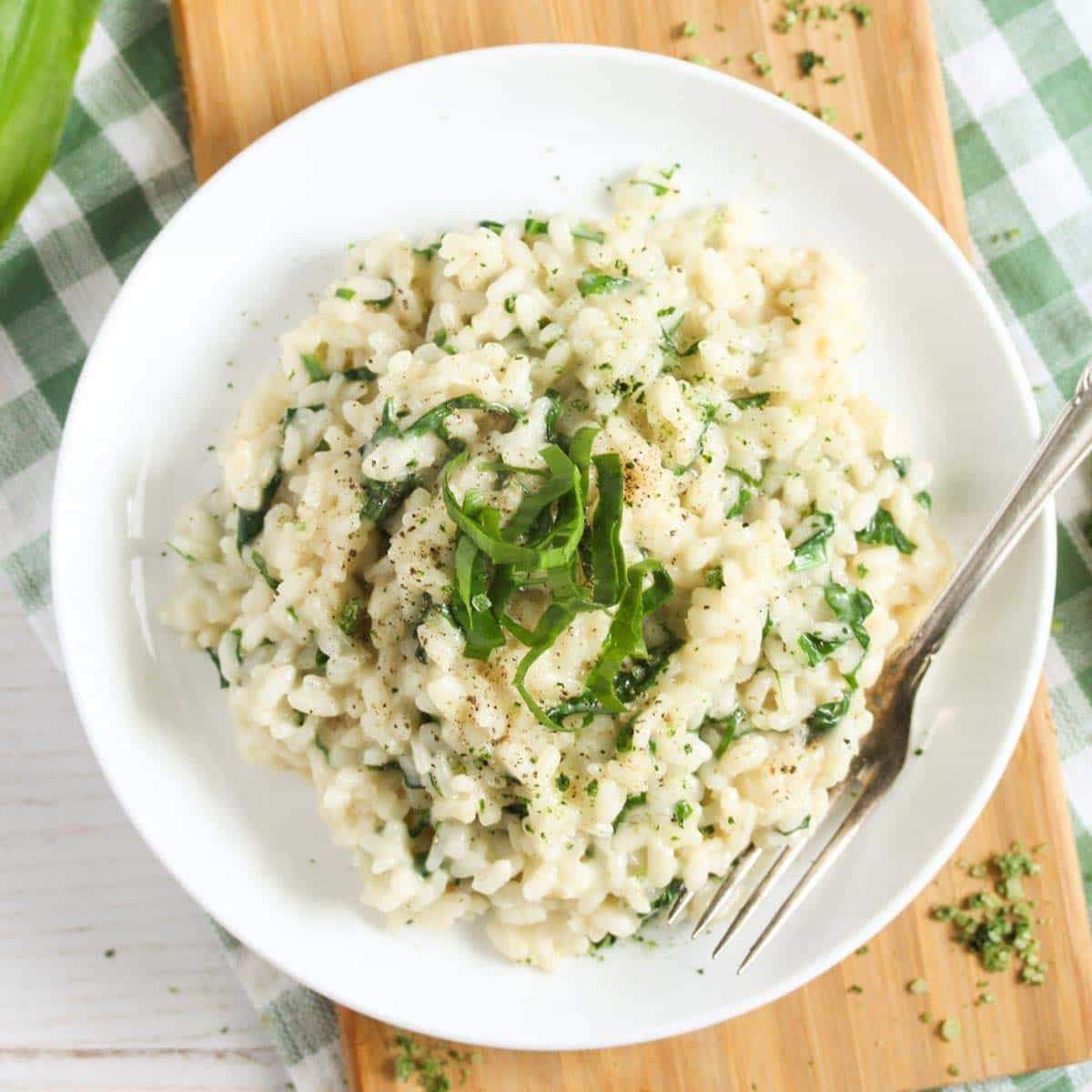 wild garlic risotto with parmesan on a small white plate.