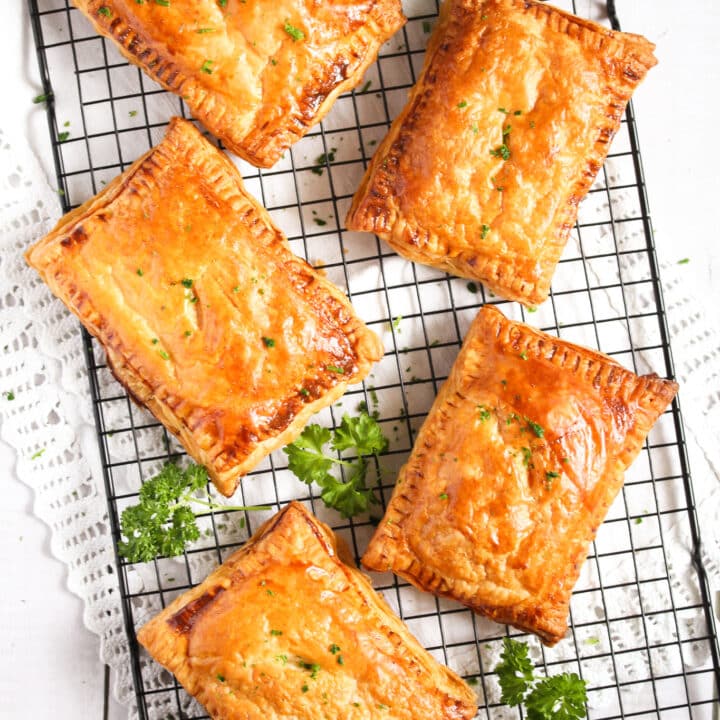 five large pasties filled with onions and cheddar cooling on a large wire rack.