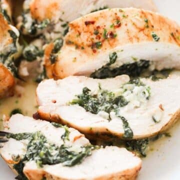 spinach stuffed chicken breast sliced on a plate.