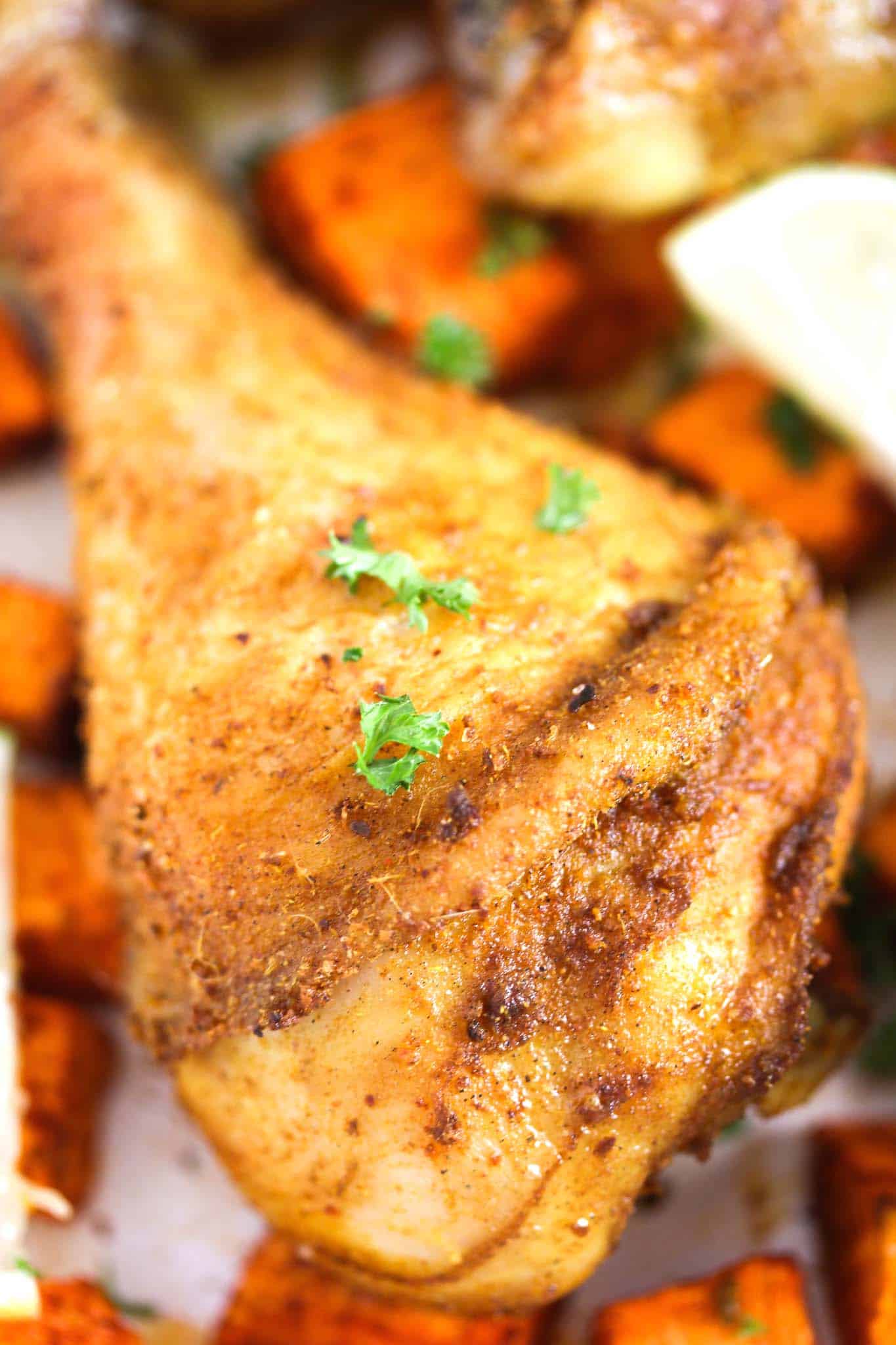 close up of one large chicken leg, roasted and sprinkled with parsley.