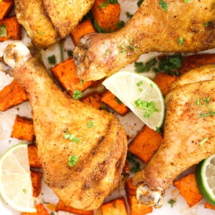 several curry drumsticks with sweet potato pieces and lime wedges in between.