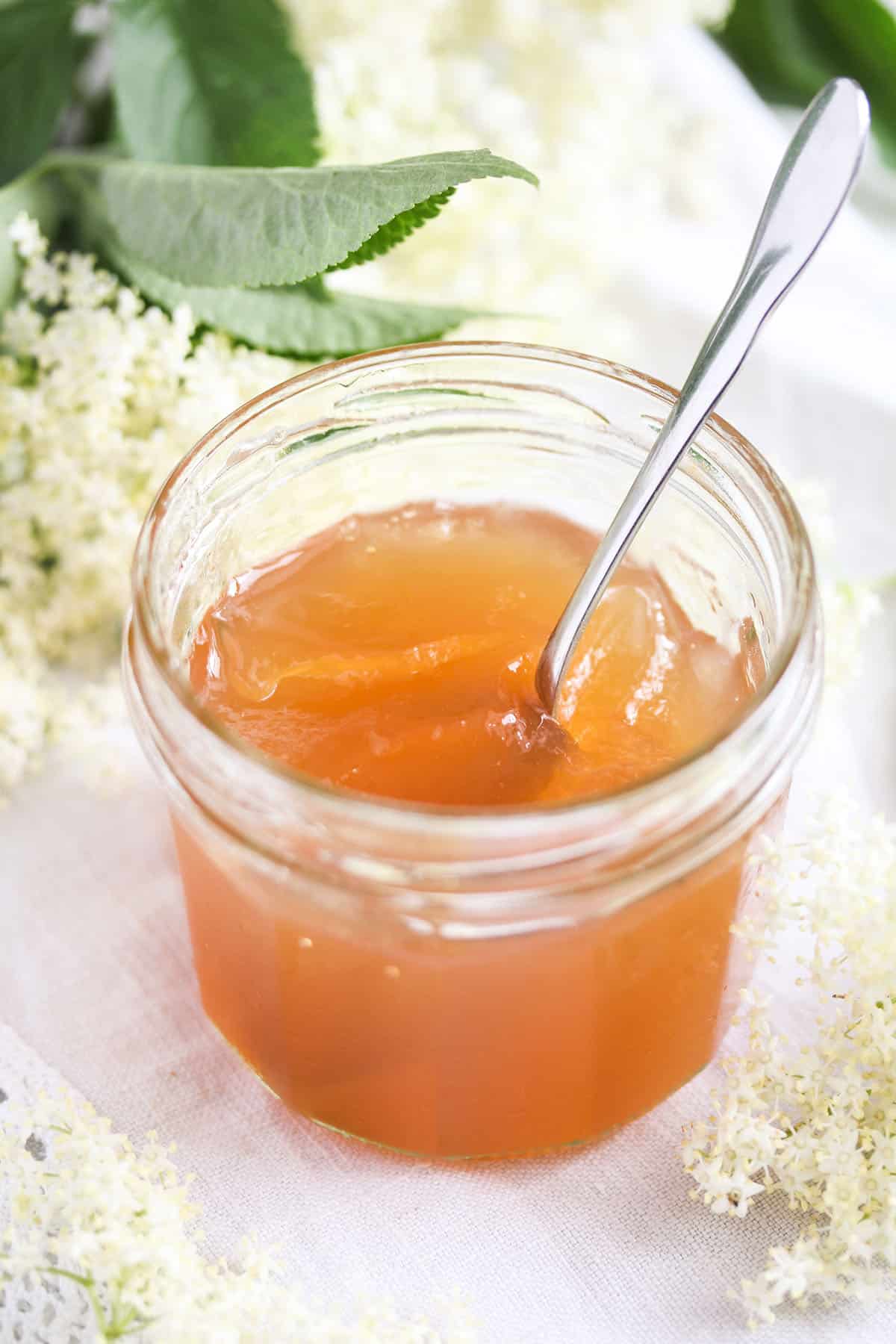 elderflower jam or jelly in a small jar with a spoon in it.