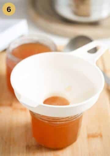 pouring elderflower jelly in a jar through a jam filler.