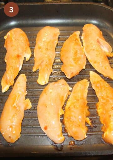 raw marinated chicken tenderloins in a grill pan.