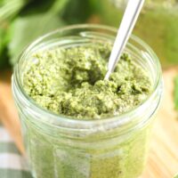 small jar of lemon balm pesto with a spoon in it.