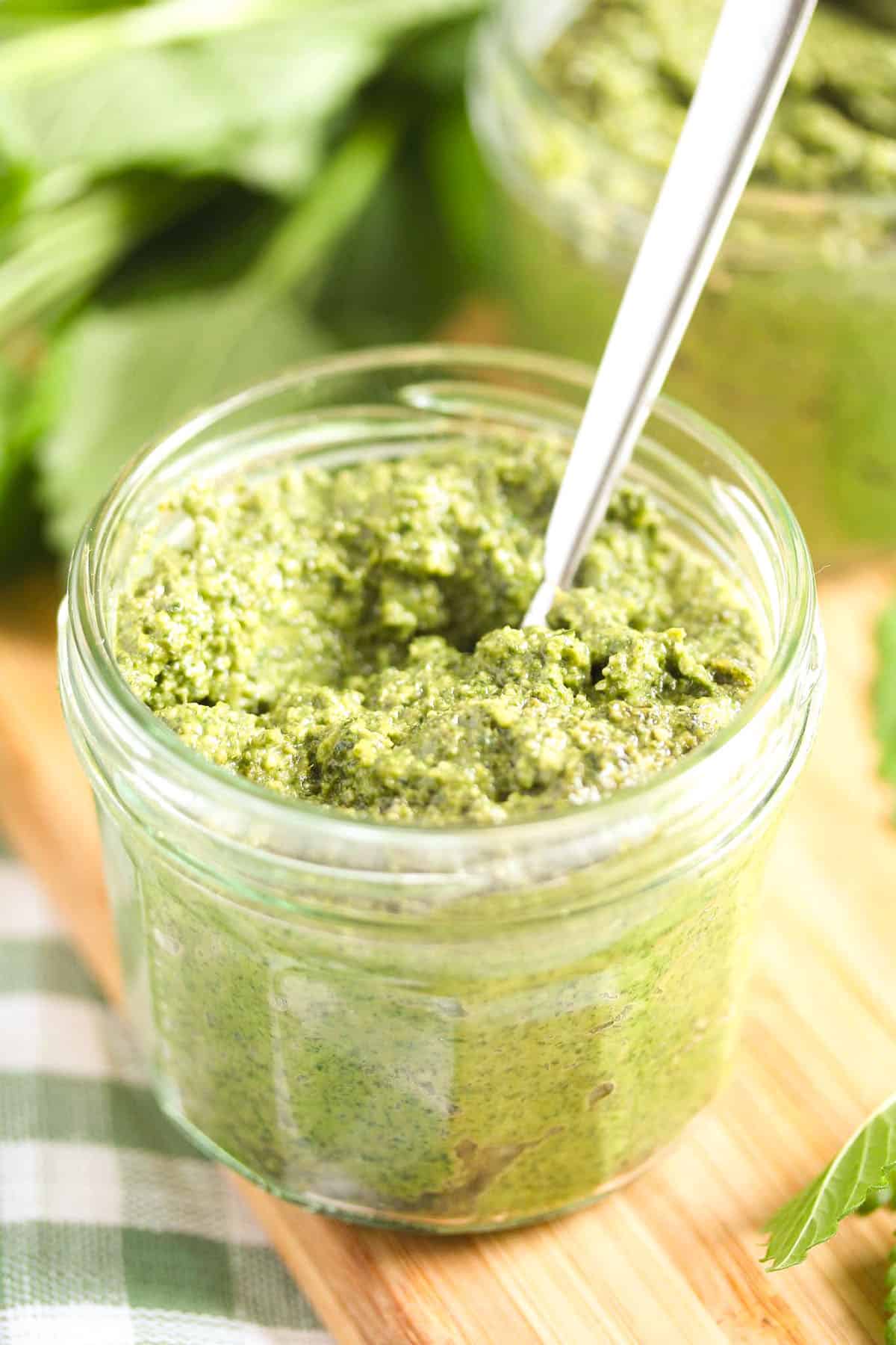 lemon balm pesto in a jar with a spoon in it.