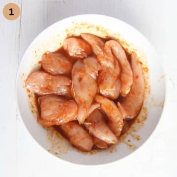 raw chicken tenders marinating in a bowl.