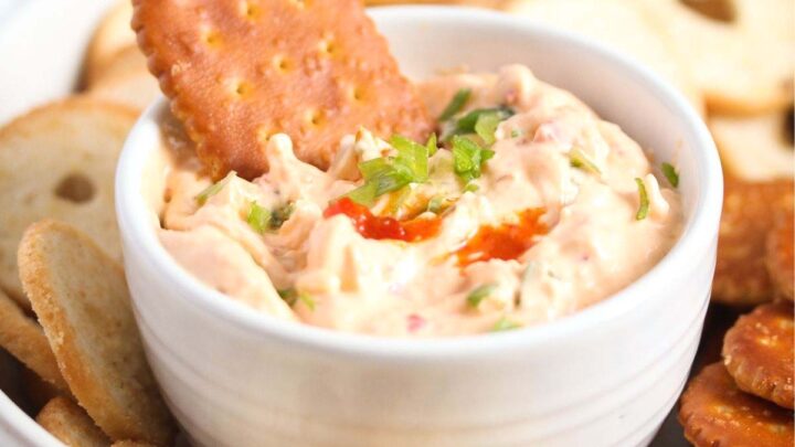 bowl of cream cheese chili dip in a large bowl surrounded by different kinds of crackers.