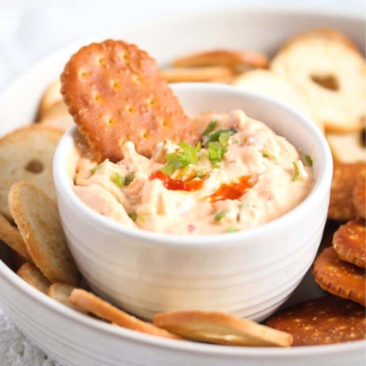 bowl of cream cheese chili dip in a large bowl surrounded by different kinds of crackers.