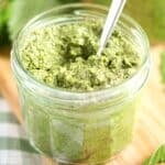 lemon balm pesto in a small jar on a wooden board.
