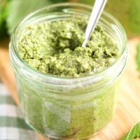 lemon balm pesto in a small jar on a wooden board.