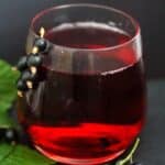 pinterest image of a glass with diluted dark red syrup made with currants.
