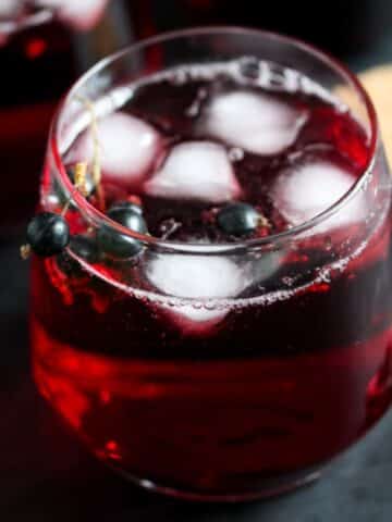 small glass with blackcurrant cordial with ice cubes.