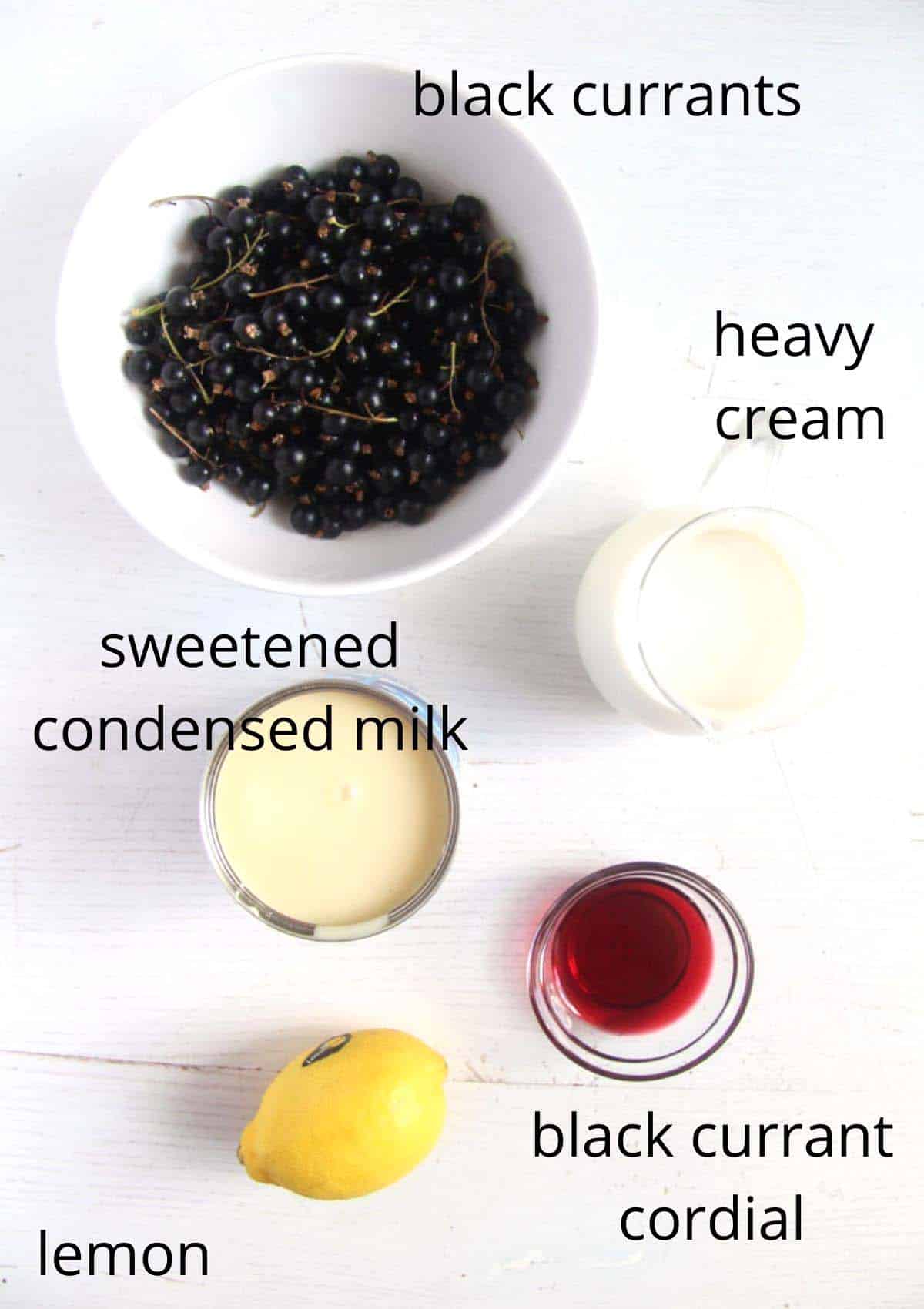 bowls with black currants, cream, condensed milk, lemon and cordial overhead view.