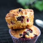 two stapled black currant muffins with leaves behind.