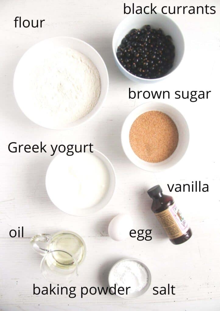 bowls with flour, currans, yogurt, sugar, vanilla, egg, oil, salt, baking powder on a white table.