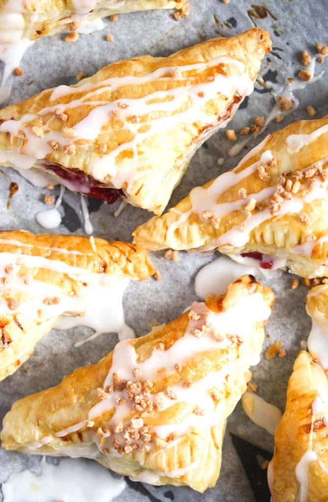 puff pastry triangles filled with fruit and glazed with icing sugar on a baking tray.