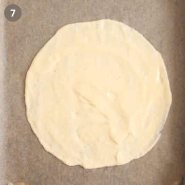 thin batter spread in a circle on parchment paper.