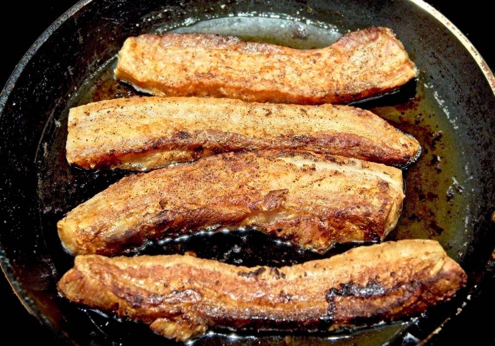 pan frying meat strips close up.