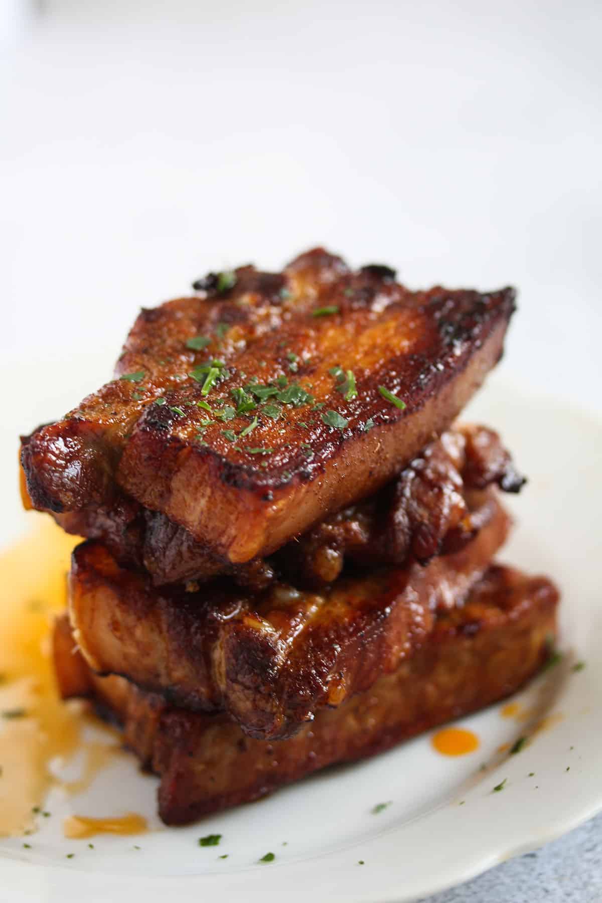 three juicy pork belly slices stapled on a plate.