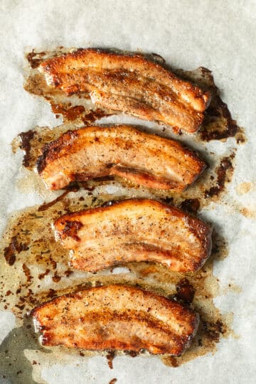 freshly baked pork belly strips on a baking sheet lined with parchment paper.