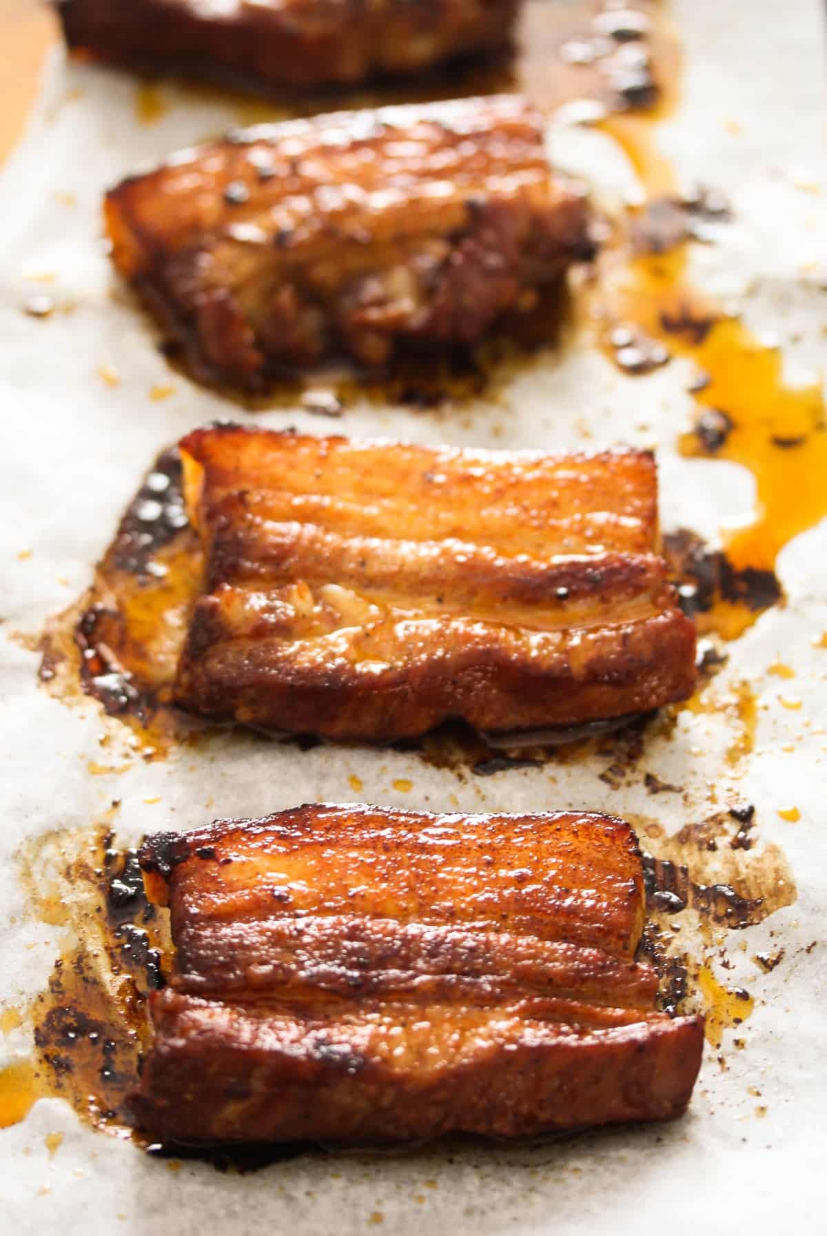 baked pork belly slices on parchment paper.