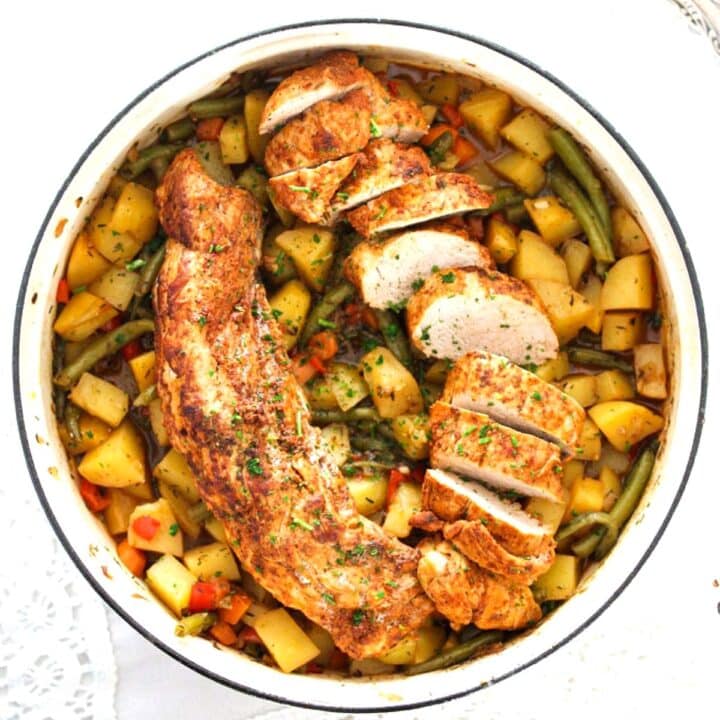 pork tenderloin in dutch oven with potatoes and vegetables.