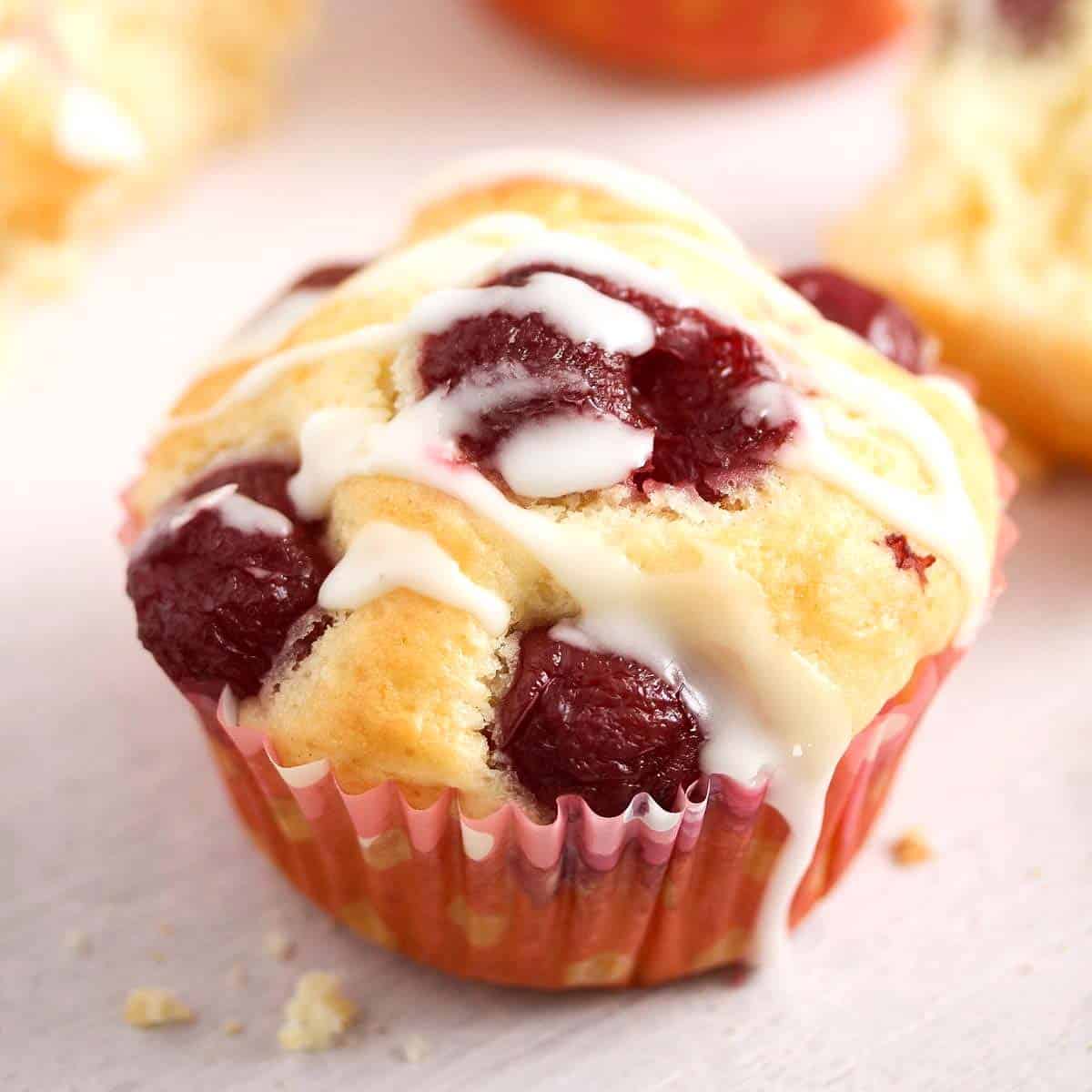 One quark muffin topped with cherries and drizzled with icing.
