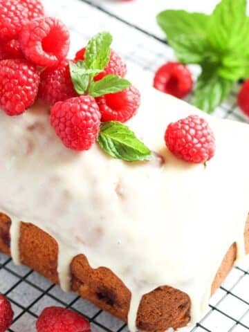 white chocolate and raspberry loaf cake on a wire rack close up.