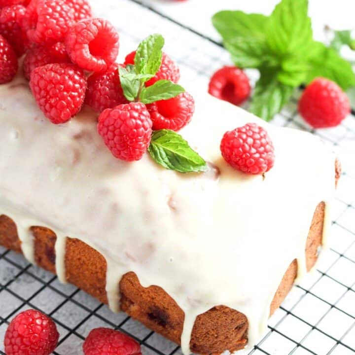 white chocolate and raspberry loaf cake on a wire rack close up.