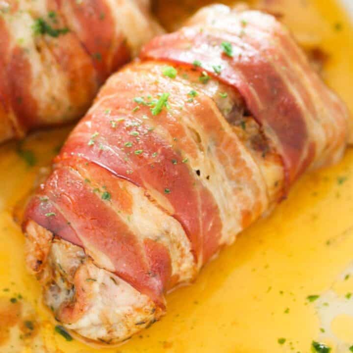 bacon wrapped chicken thighs close up in a pool of cooking juices.