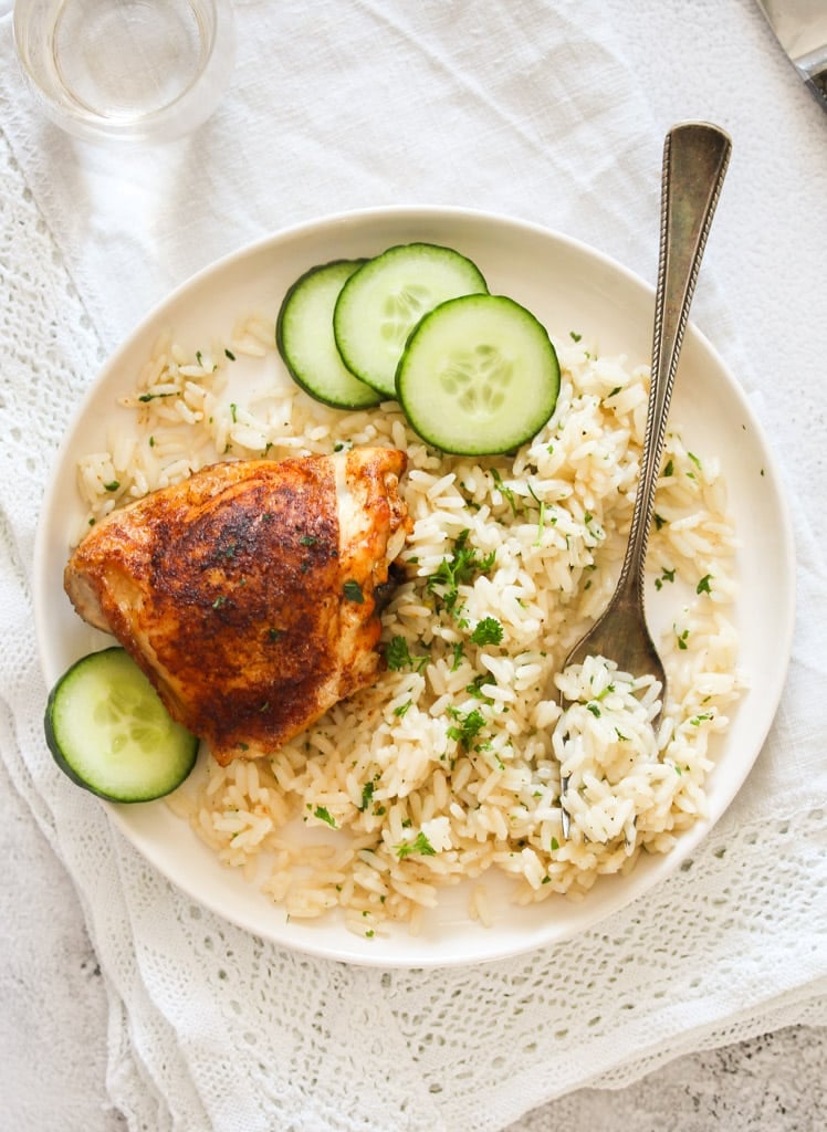 overhead picture of a plate with rice, chicken and cucumber slices.