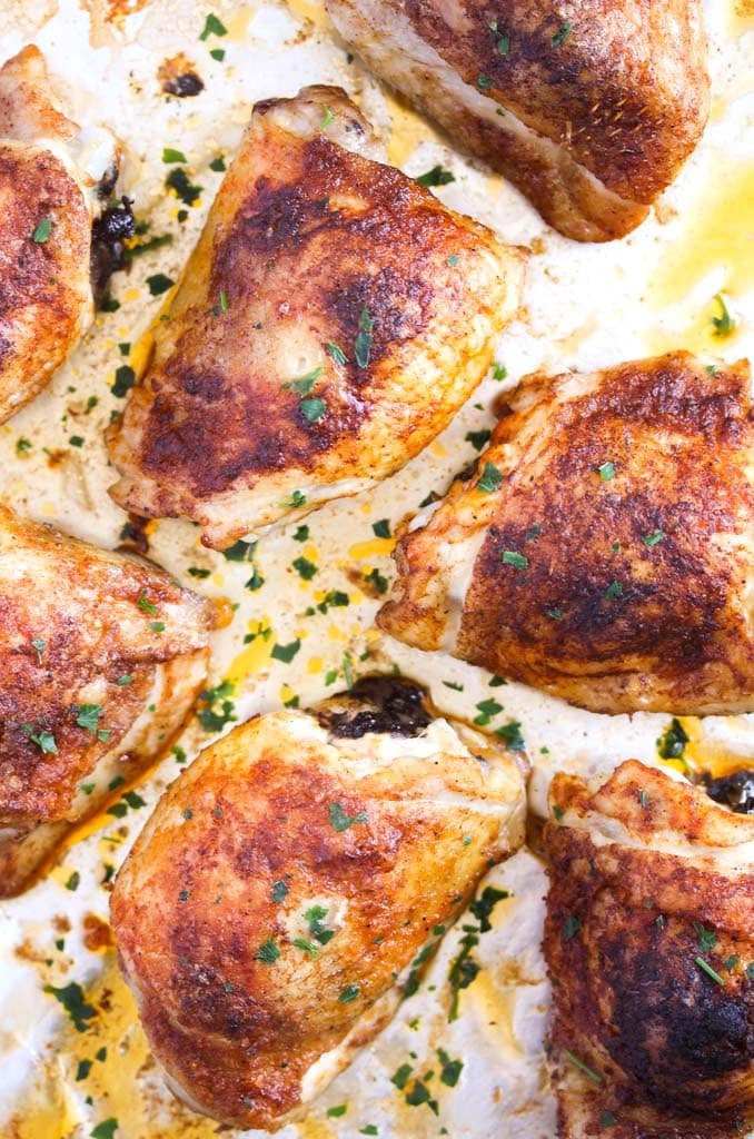 overhead view of a baking tray with baked chicken thighs.