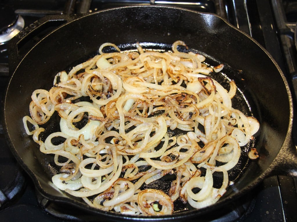 caramelizing sliced onions in a cast-iron skillet.