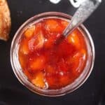 overhead view of a jar with peach jam without pectin on a dark board.