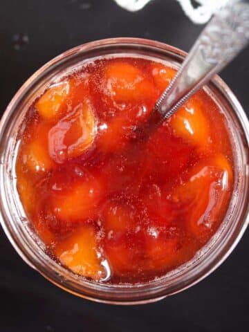 overhead view of a jar with peach jam without pectin on a dark board.