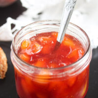 jam preserves without pectin in a small jar on a black board with a white cloth behind.