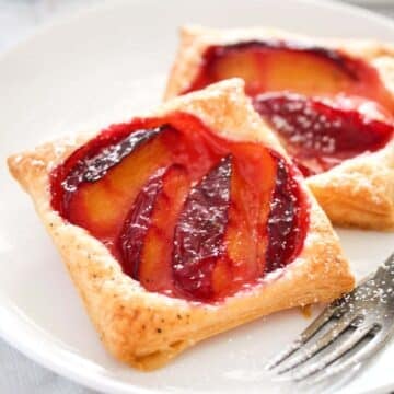 puff pastry plum tarts on a plate close up.