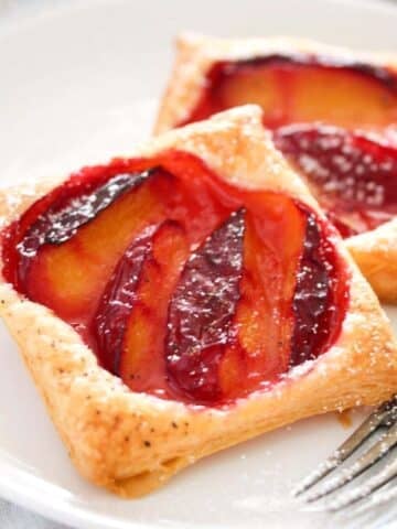 puff pastry plum tarts on a plate close up.
