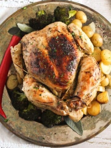 roast chicken in a dutch oven served on a vintage plate with chili and potatoes.