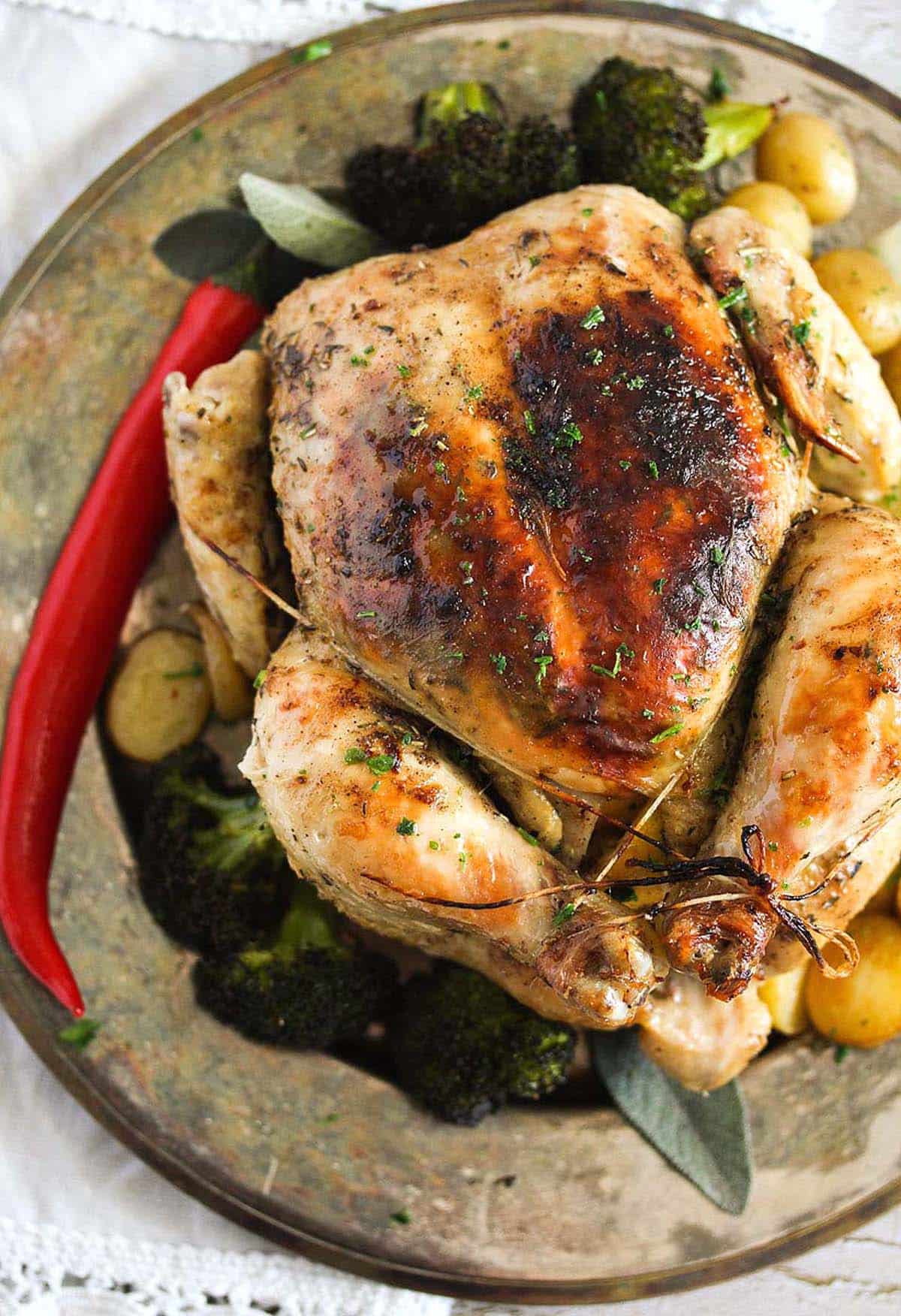 crispy whole chicken cooked in a dutch oven and served on a vintage plate.