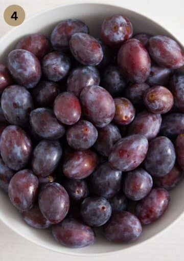 a bowl full of italian or prune plums to use for making cake.