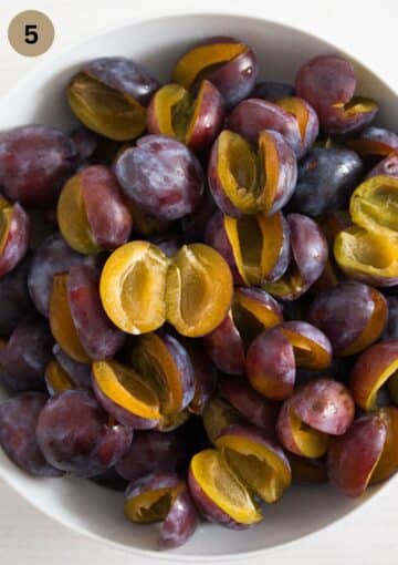 italian plums in a bowl prepared to be put on german plum cake.